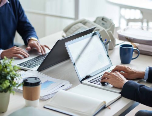 Cropped image of business people working on laptops in office